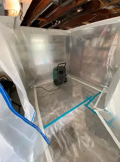 Plastic containment walls around a dehumidifier in a gutted room