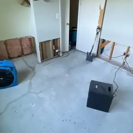 Air movers and a dehumidifier drying a room with the lower drywall removed