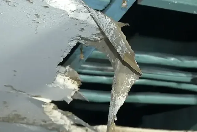 Pipes coated in ice behind a broken-open ceiling after a hard freeze